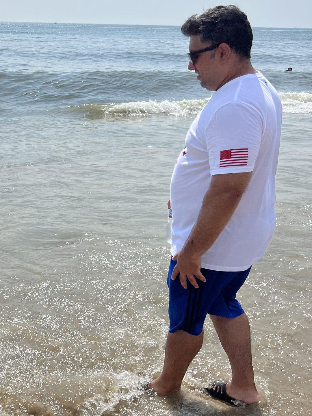 Hammad at the beach in July 2023, standing in the surf with his t-shirt on